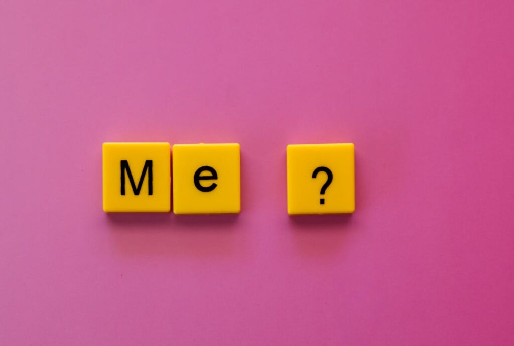 The Art of Drawing Readers In: Your attractive post title goes here Yellow letter tiles forming 'Me?' against a vibrant pink background, offering a playful concept.