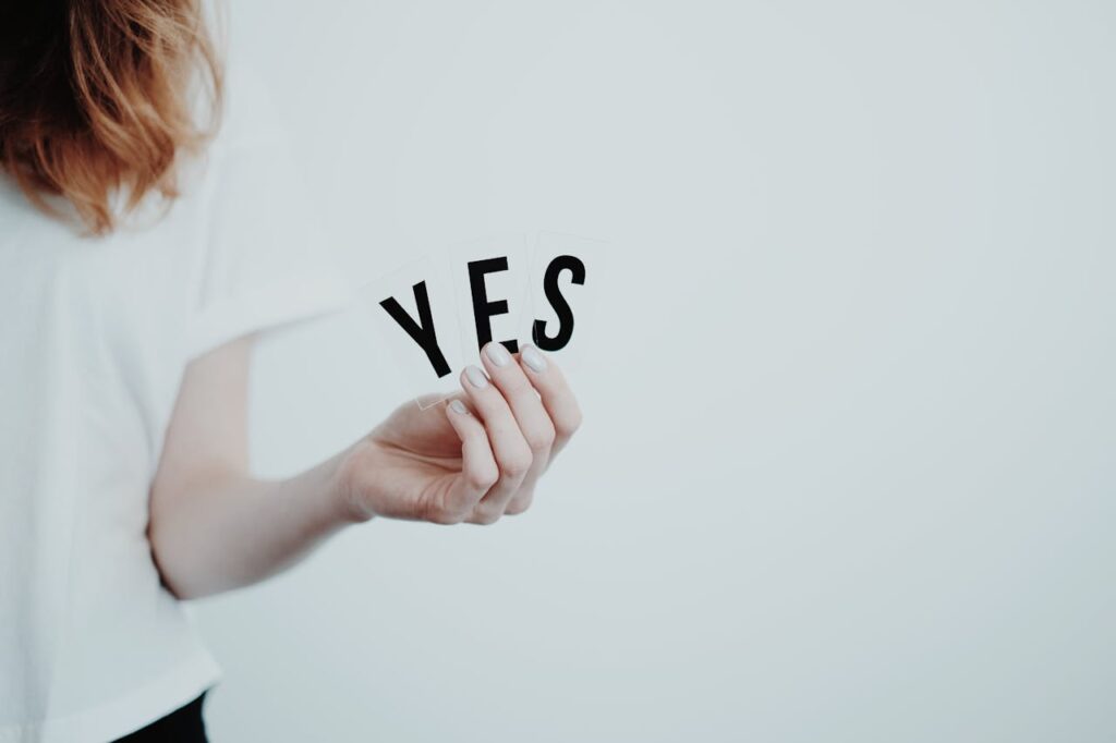 Close-up of a hand holding cards with the word 'YES' on a white background.
