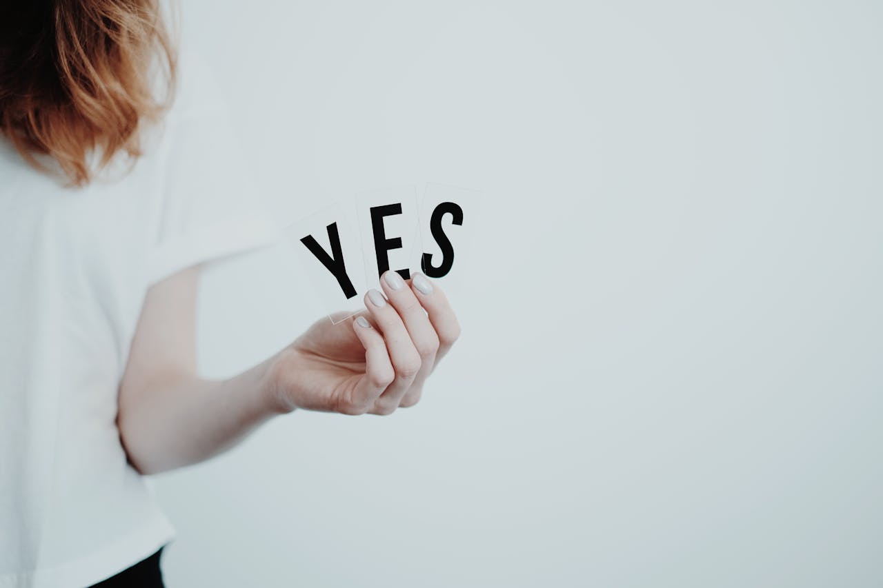 Close-up of a hand holding cards with the word 'YES' on a white background.